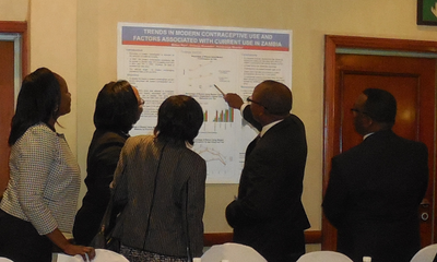 Attendees review a poster at the Zambia close out event.